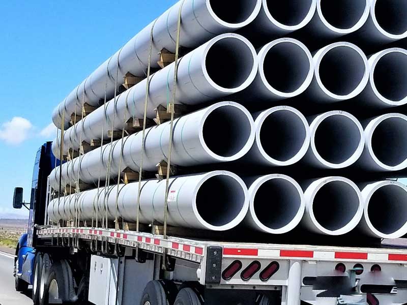 Low loader carrying pipes to illustrate trucking companies in Dallas supporting water infrastructure works