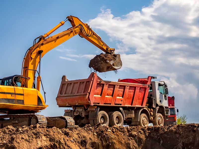 working excavator filling a dump truck to illustrate dump truck hauling near me